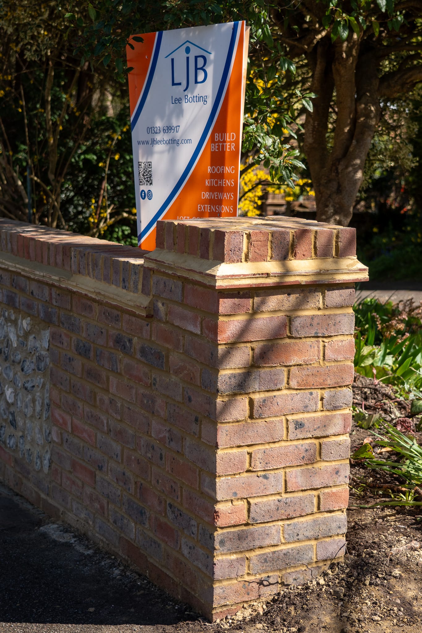 New brick pier and coping on a traditional flint boundary wall