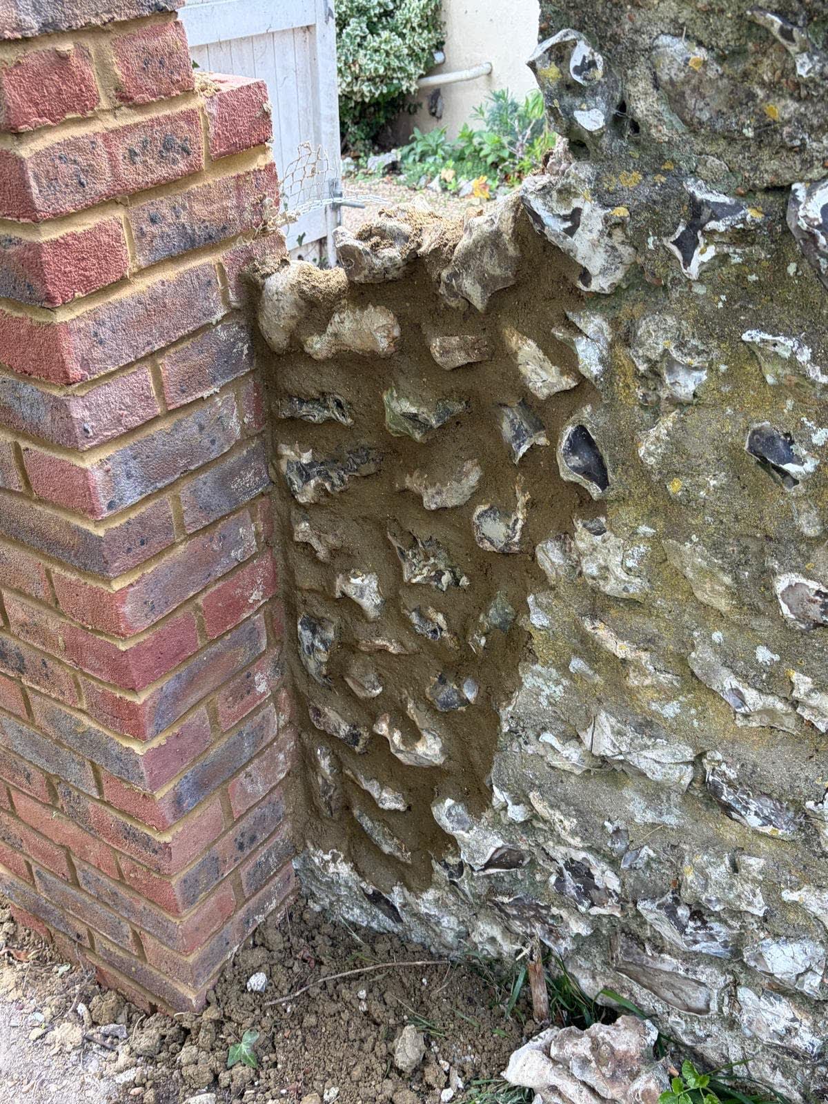 Close view of new brickwork joined to an existing flint wall