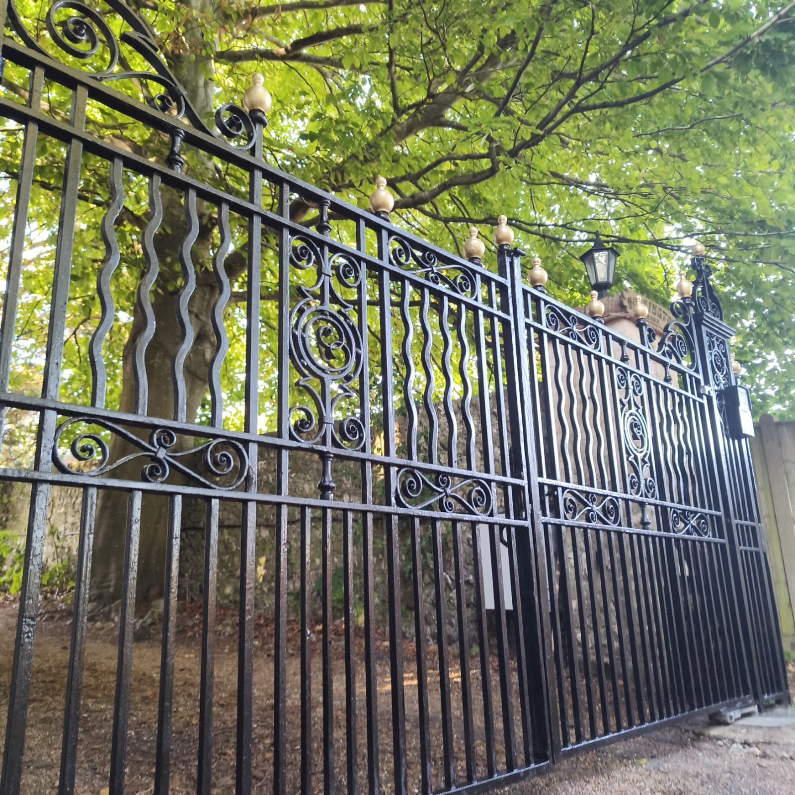 Restored wrought-iron driveway gates with decorative metalwork