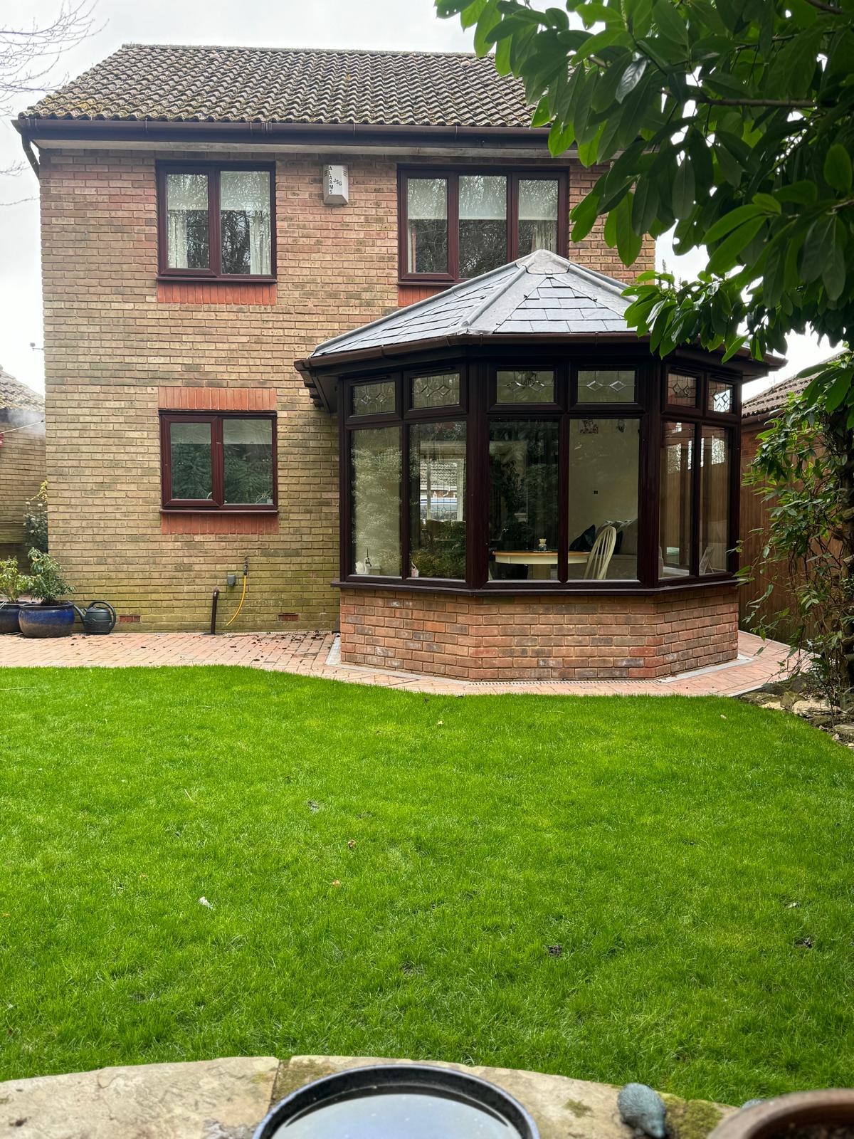 Conservatory beside a landscaped lawn and patio