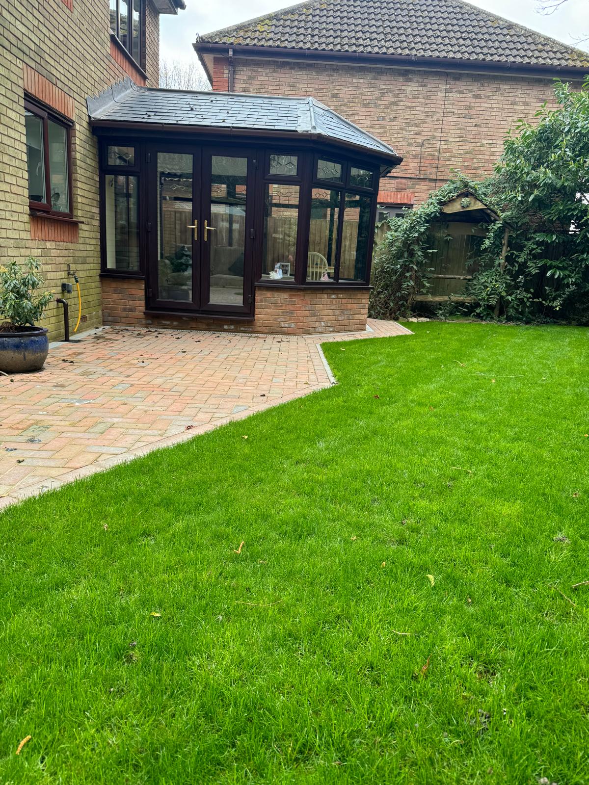 Finished lawn and paved patio outside a glazed garden room