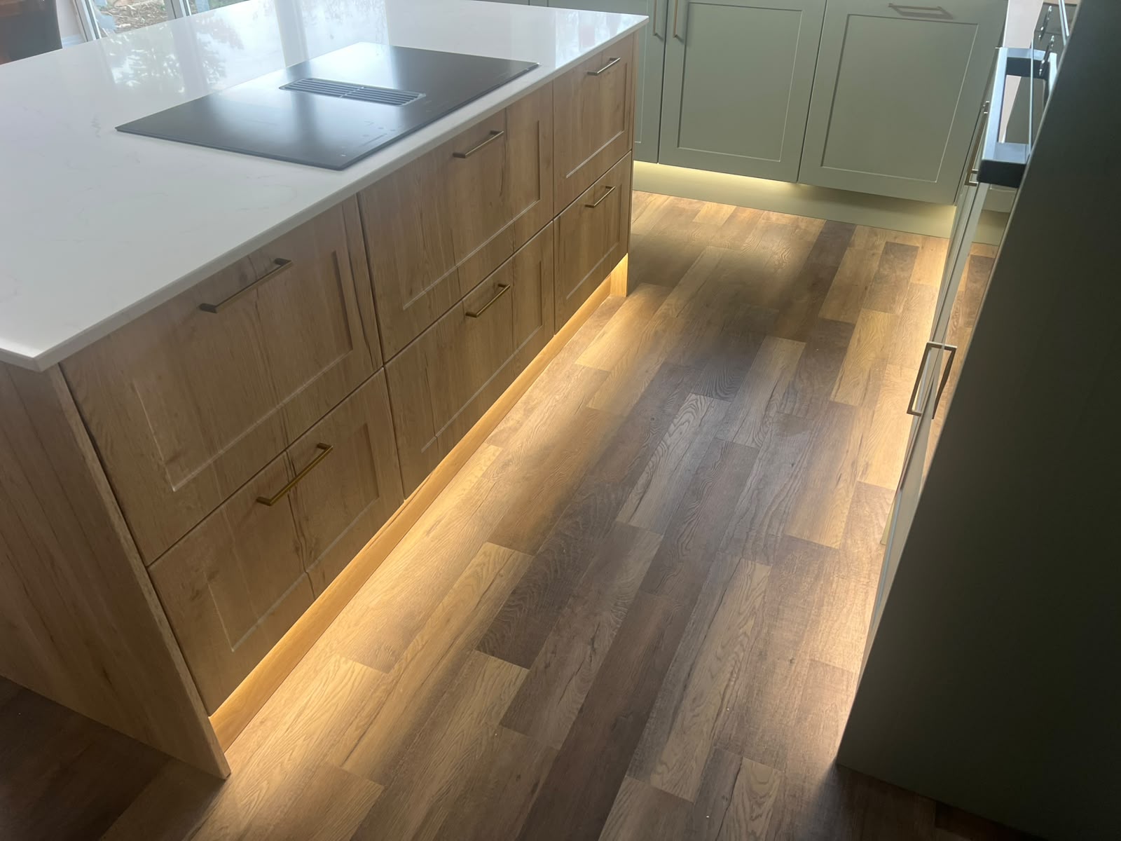 Kitchen base cabinets with integrated lighting and wood-effect flooring