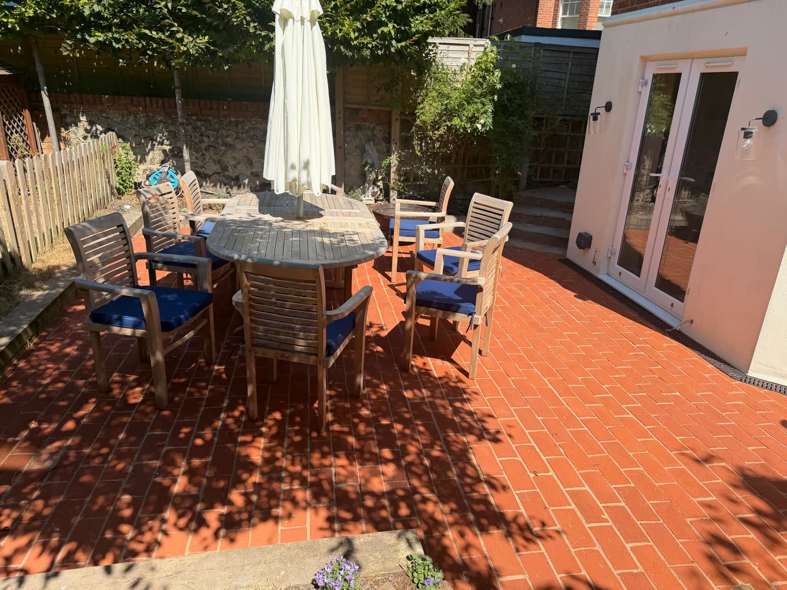 Finished red brick patio beside a rendered home